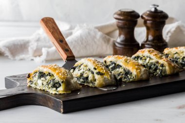 Tahta bir tahtanın üzerinde ev yapımı ıspanak ve peynirli börek servis etmeye hazır.. 