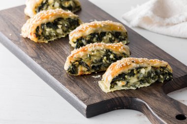 Ispanak ve feta hamur işleri ahşap bir tahtanın üzerinde, paylaşmaya hazır.. 