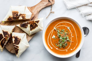 Brokoli lahanasıyla süslenmiş ev yapımı kırmızı biber çorbası ve gevrek ambalajlarıyla servis ediliyor.. 