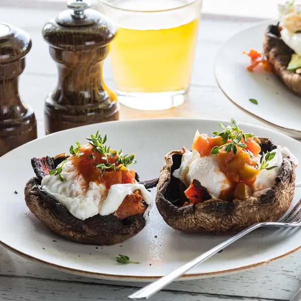 stock image A close up of a serving of portobello mushroom Eggs Benedict topped with salsa and thyme.