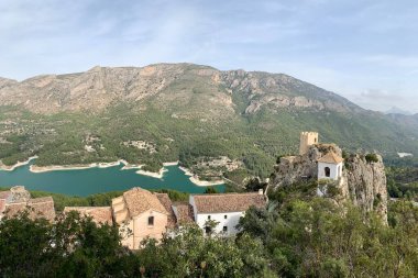 İspanya Alicante 'deki Guadalest Kalesi' nin panoramik manzarası. Dağın tepesinde eski bir ortaçağ kasabası. Arka planda büyük bir rezervuar var..