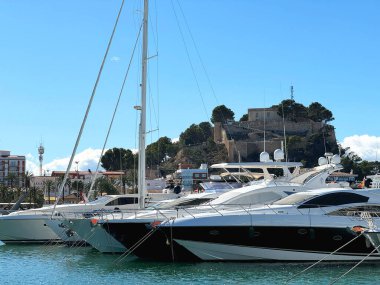 Güneşli bir günde İspanya 'nın Denia limanında birkaç tekne. Arka planda eski ortaçağ kalesi var..