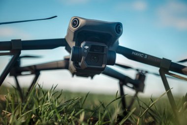 DJI Maviç 3 insansız hava aracının açık bir arazinin ortasındaki uzun çimlerde dinlenirken çekilmiş yakın plan görüntüsü. Sahne, Ukrayna ile Rusya arasında devam eden çatışmayı kurnazca yansıtıyor.