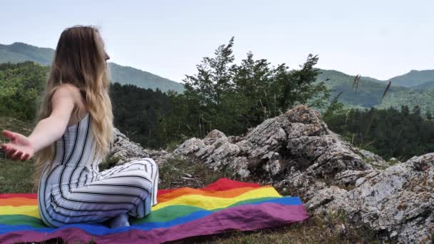 Dağlardaki Renkli Lgbt Bayrağı Üzerinde Meditasyon Yapan Lezbiyen Sarışın Kadın — Stok video