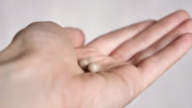 The female hand holds pills vitamins omega, spirulina, iron and is treated . Close-up and points your finger up. Nurse gives pills to the patient