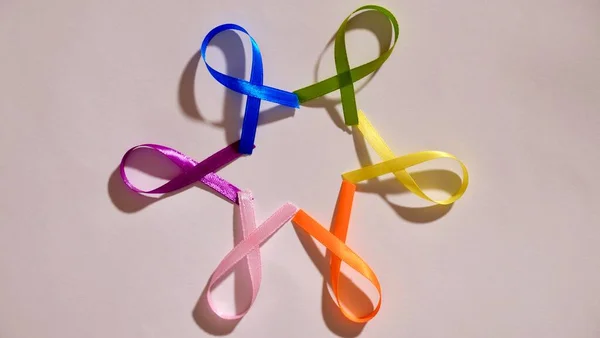 Cancer disease symbol with colored ribbons on white background close-up on world Cancer Awareness Day