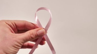 Breast Cancer disease symbol with pink ribbon in hand on white background close-up on world Cancer Awareness Day 4 February 