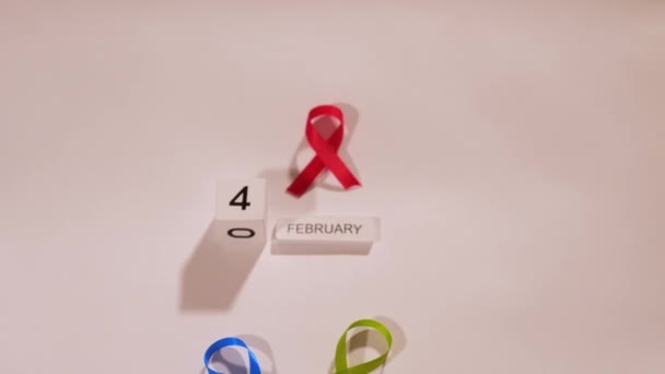 世界の白い背景に赤いリボンを持つがんの病気のシンボルがん啓発日2月4日 — ストック動画