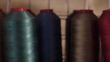 Fabrikadaki üretim sırasında bir dikiş makinesi için bir iplik yumağı. Terzi kadın el işi diker. Kimse yok.