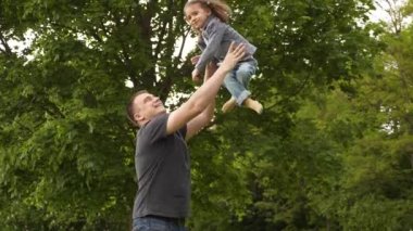 Mutlu genç baba ve küçük kız yazın yeşil parkta Uluslararası Babalar Günü 'nde eğleniyor ve gülüyorlar. 