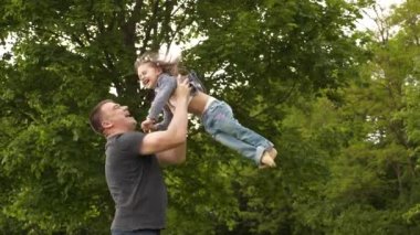 Mutlu genç baba ve küçük kız Uluslararası Aile Babaları Günü 'nde dışarıda yeşil parkta eğleniyor ve gülüyorlar. 