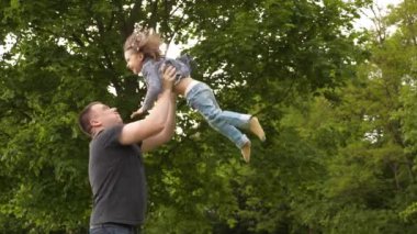 Mutlu genç baba ve küçük kız Uluslararası Aile Babaları Günü 'nde dışarıda yeşil parkta eğleniyor ve gülüyorlar. 