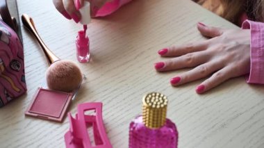 Bir kadın manikür yapıyor, tırnaklarını pembeye boyuyor, Barbie tarzı, yakın plan. Bayan gelin bekarlığa veda partisi için hazırlanıyor.