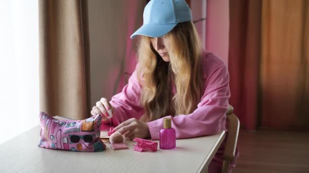 女性はマニキュアを作り テーブルの自宅でバービーのスタイルで彼女の爪をピンクに塗ります レディー ブライドは結婚式の前に独身パーティーの準備をしています 長い髪のブロンドの女の子 — ストック動画
