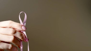 Kadın elinde pembe sembolik kurdele, sembol. Dünya Göğüs Kanseri Günü. Yakından, soyutlanmış, pembe , 