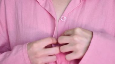 Bir kadın, bir kız pembe bir keten takım elbise giyiyor. Yüz yok, yakın çekim, kopyalama. Arkadaş bekarlığa veda partisine hazırlanıyor.