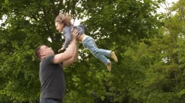 Mutlu genç baba ve küçük kız Uluslararası Aile Babaları Günü 'nde dışarıda yeşil parkta eğleniyor ve gülüyorlar. 