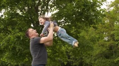 Mutlu genç baba ve küçük kız Uluslararası Aile Babaları Günü 'nde dışarıda yeşil parkta eğleniyor ve gülüyorlar. 