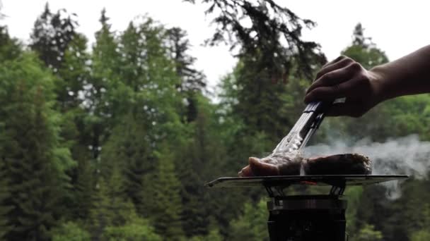 一个手下人做饭 在一个综合系统上准备蒸肉 在森林里烧烤 近距离远足 在自然界中的替代格栅上烹调 — 图库视频影像