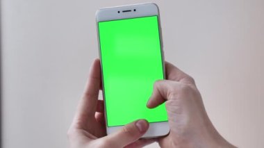 Beyaz izole edilmiş arka planda yeşil ekranlı POV kaydırmalı telefon kadın ellerinde. Gerçek hayatta modern teknoloji