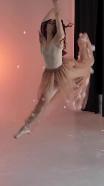一名跳芭蕾舞的女芭蕾舞女青年在摄影棚拍照时摆出姿势 用粉红的背景轻柔地移动着她的胳膊和手指 动作缓慢 拥有一头长发的棕色头发女士 — 图库视频影像