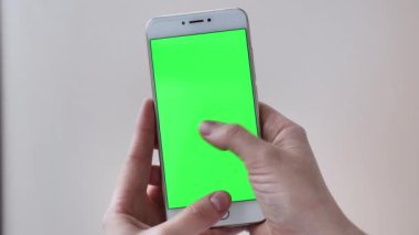Beyaz izole edilmiş arka planda yeşil ekranlı POV kaydırmalı telefon kadın ellerinde. Gerçek hayatta modern teknoloji