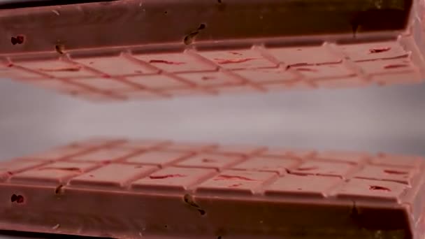 クローズアップミルクルビーチチョコレートバー ナッツアーモンドとイチゴの塊 灰色の背景に表示され 反射面に配置され 自分自身の鏡像を作成します — ストック動画