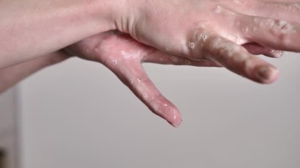 白い背景に汚れや細菌を閉じ込めるために石鹸と水で女性の手を洗う 指は穏やかにそしてゆっくり動きます — ストック動画