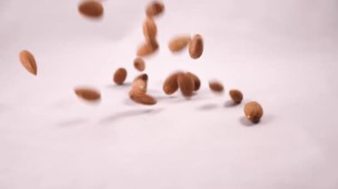 Bademler yavaş çekimde beyaz arka plana dökülüyor. Fındık yaklaşık 15 cm yükseklikten düşer ve yumuşak bir gümbürtüyle yüzeye düşer. Saniyede 240 kare çerçeve hızı