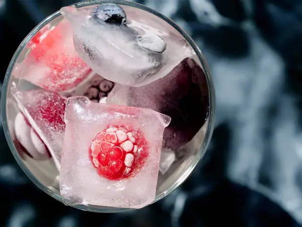 Mevsimlik vitamin vitaminleri, ahududu, çilek, kiraz, yaban mersini, böğürtlen, böğürtlen, böğürtlen ve meyvelerin korunması için dondurulmuş böğürtlen ve meyveli bir bardak.