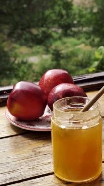 Elmalar kırmızı ve bal kavanozuyla dilimlenmiş geleneksel Yahudi bayramı Rosh Hashana 'da güneşli bir günde pencere kenarındaki ahşap bir masada. Yakın çekim, dikey