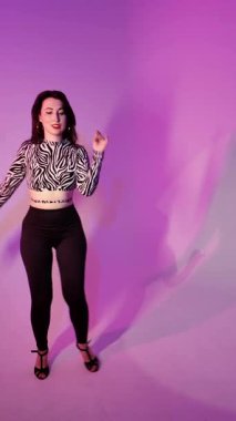 Mor ışıklı arka planda Bachata Lady Style, genç esmer beyaz kadın dans eden kadın koreografisi. dikey