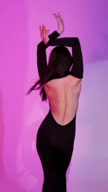 Bachata Lady Style, neon mor arka planda, genç esmer beyaz kadın dans eden kadın koreografisi. dikey, genel olarak yakın plan