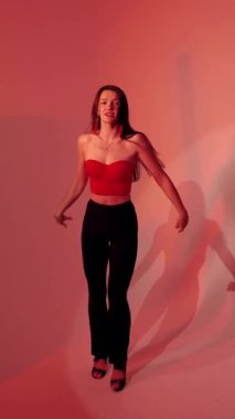 Kırmızı ışıklı arka planda Bachata Lady Style, genç esmer beyaz kadın dans eden kadın koreografisi. dikey, genel olarak yakın plan