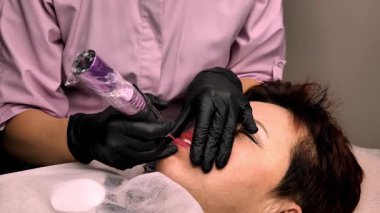 Kalıcı dudak makyajı. 50 yaşını geçmiş güzel bir kadın. Bir güzellik salonunda. Bir güzellik uzmanı yüzüne dövme yaptırıyor.. 