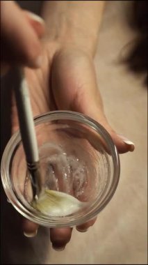 Güzellik uzmanı, yüz derisi için temizleyici jeli bir kasede karıştırıyor, yakın çekim, üst görünüm, dikey. Güzellik salonunda gençleştirici bir prosedür.