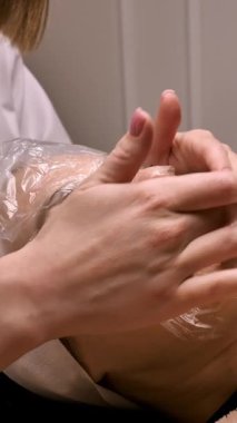 Bir güzellik uzmanı, bir güzellik salonundaki deriyi temizlemek için kadın müşterisini yüzündeki gözeneklerin genişletilmesi prosedürüne hazırlar. yakın çekim, dikey