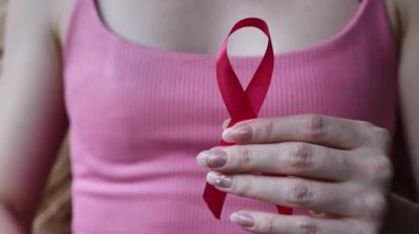 Küçük Göğüs Kanseri Ayı kavramı, elinde pembe sembol kurdelesi tutan kadın, yakın plan.