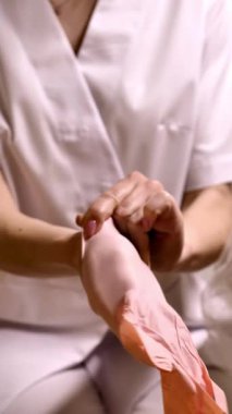 Bir profesyonel, klinik, tıbbi ya da güzellik ortamında güvenlik ve hijyeni vurgulamak için pembe tek kullanımlık eldiven takar.