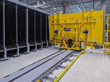 Modern cam fabrikasında düz cam çarşafları düzenleyen otomatik cam karıştırıcı..