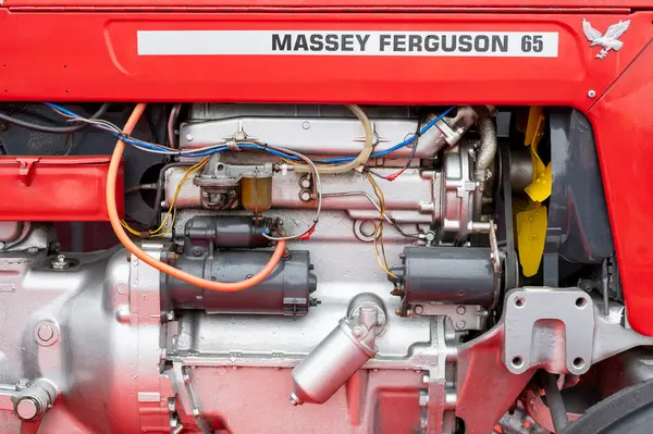 Bir Massey Ferguson 65 traktör motorunun detaylı yakın plan görüntüsü karbüratör, marş ve kablo gibi görünür parçaları gösteriyor..