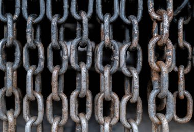 Eski, paslı, delikli zincirler. Zincirlerin hepsi farklı boyutlarda ve birbirlerine bağlılar..
