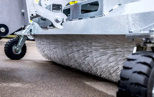 Bu görüntü, şehir yollarını temizlerken modern bir sokak süpürgesinin tasarım ve işlevselliğine odaklanan detaylı bir yakın çekimini içeriyor..