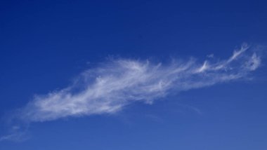 Gökyüzünde mavi arkaplanı olan uzun bir bulut. Bulut uzun ve ince ve gökyüzünde görülebilen tek şey.