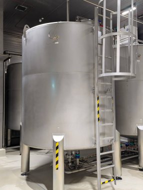 Modern endüstriyel bir fabrikada güvenlik merdiveni olan büyük paslanmaz çelik bir tank.