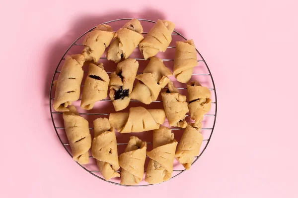 stock image Unbaked shortbread rolled cookies with plum jam filling on a metal rack. Top view.