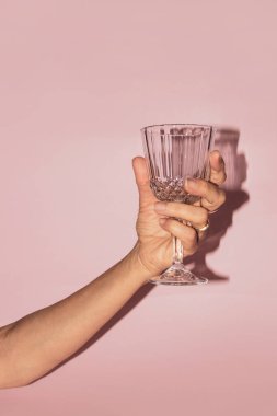 Boş bardağı pembe arka planda tutarken