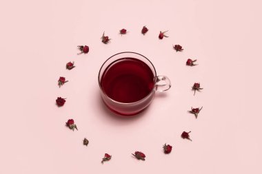 Bitki çayının etrafındaki kırmızı gül goncalarından oluşan bir çember.