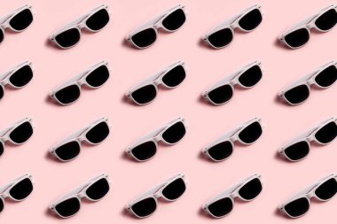 Pastel pembe arka planda beyaz güneş gözlüğü deseni