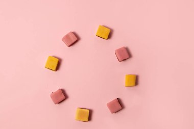 Pembe arkaplanda pembe ve sarı meyan kökü şekeri çemberi